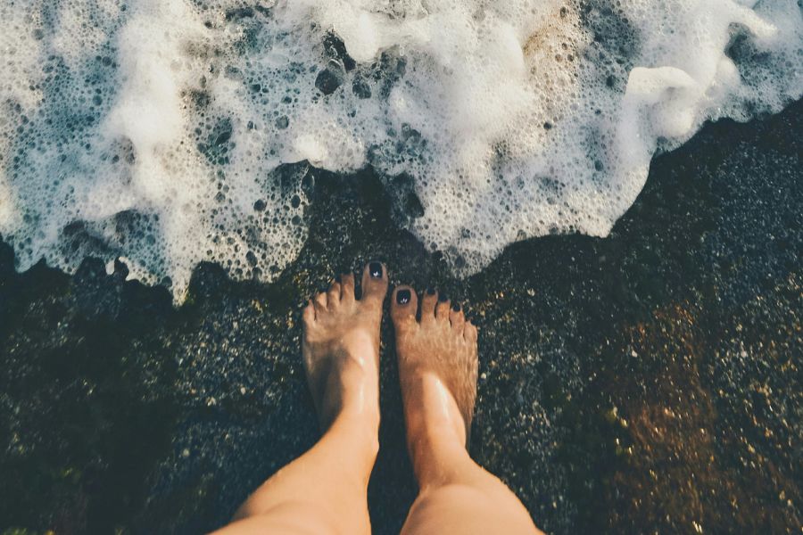 piernas de una mujer en la orilla de la playa