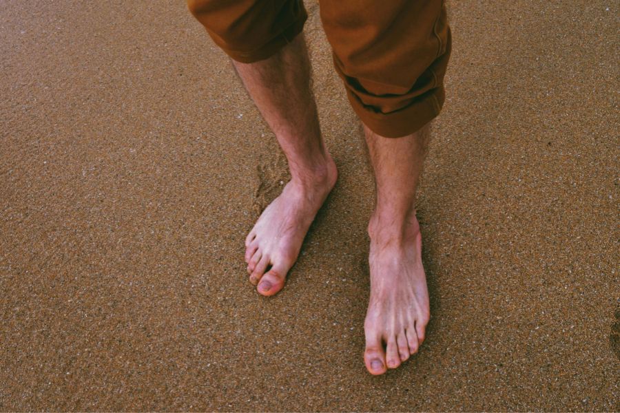 pies descalzos de un hombre caminando por la playa