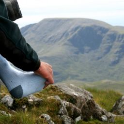 persona tocando su pie sobre el calcetín al lado de un paisaje montañoso