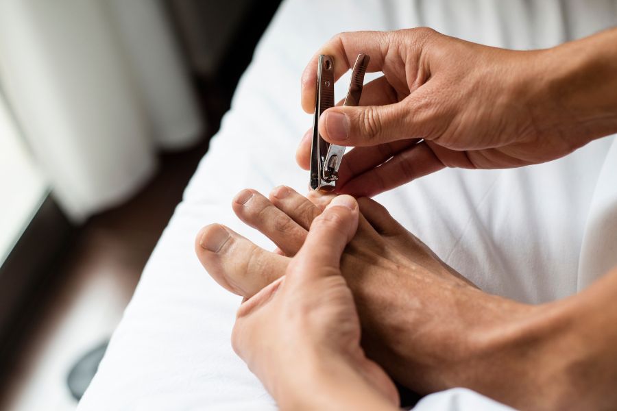 una persona cortándose las uñas de los pies